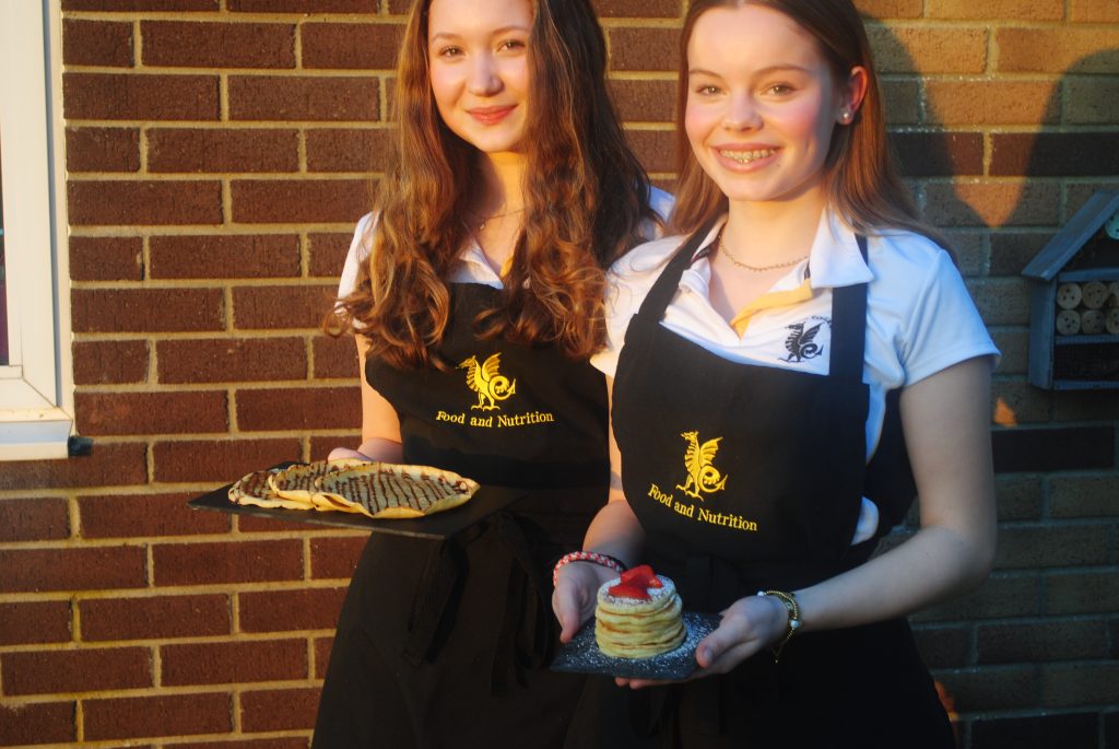 Two Queen's College students holding pancakes