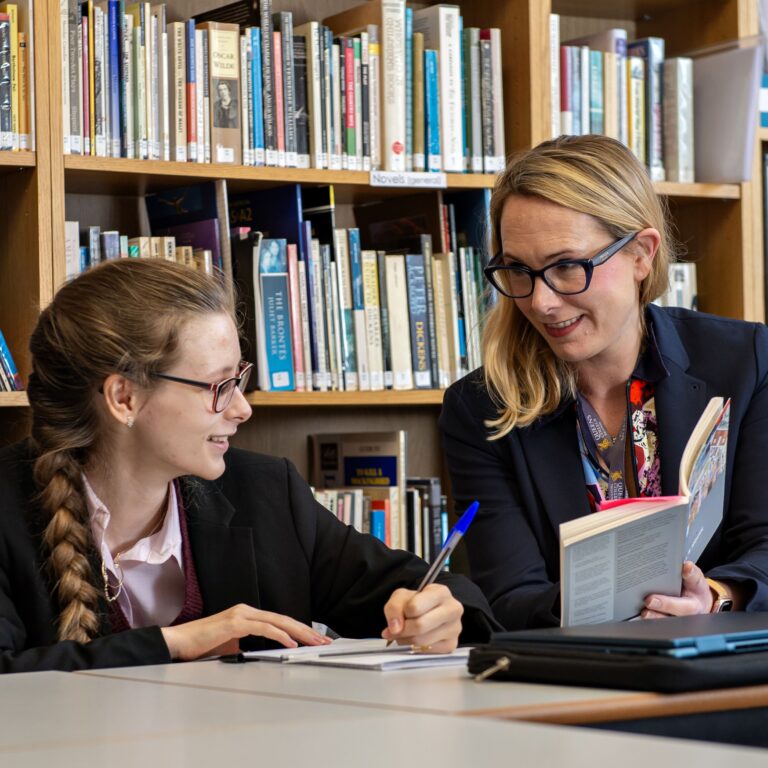Queen's College pupil reading a book with a teacher