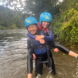 Two girls in a river in wetsuits.