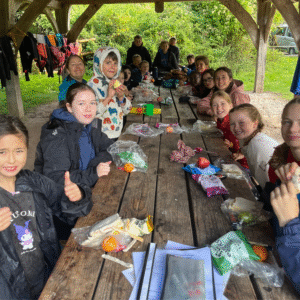 Group of pupils eating outside at a table.