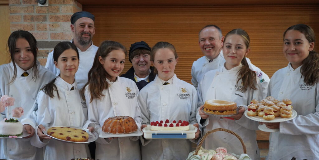 A group of pupils holding cakes at a bake sale