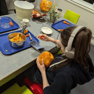 Boarder carving a pumpkin.