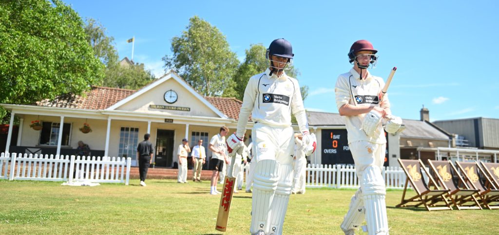 Two pupil walking next to the Queen's cricket pavilion.